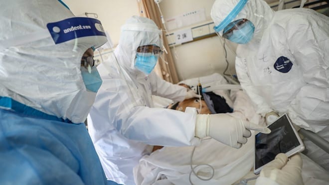 Bác sĩ tại một bệnh viện ở Vũ Hán khám cho một bệnh nhân COVID-19 /// AFP