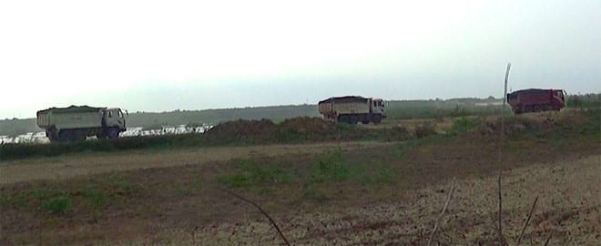 Xe tải chở đất, cát nối đuôi nhau chạy rầm rầm trên hồ Biển Lạc Ảnh: Thanh Niên