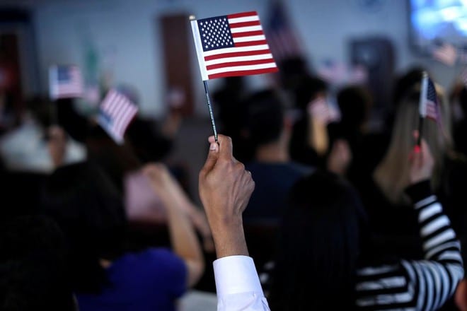 Những tân công dân Mỹ vẫy cờ Mỹ sau khi tuyên thệ trung thành trong một buổi lễ nhập tịch ở Newark, bang New Jersey /// Reuters