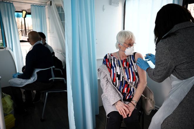 Một người dân được tiêm vắc xin Covid-19 bên trong xe buýt trưng dụng làm trung tâm tiêm chủng di động ở thủ đô London của Anh ngày 14.2 /// REUTERS