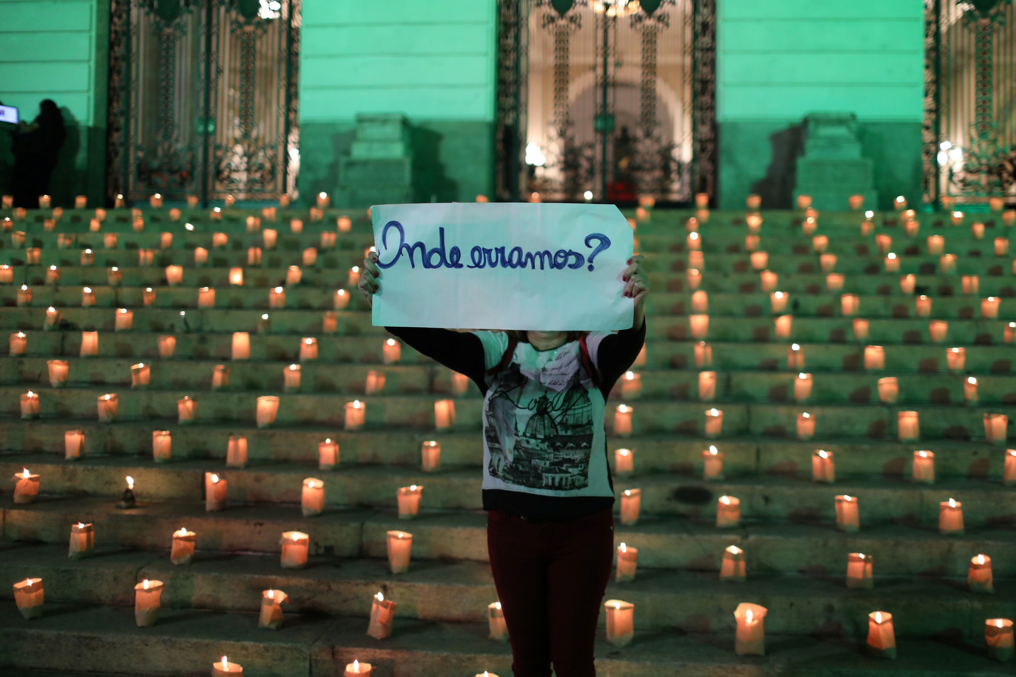 Người biểu tình cầm tấm bảng với dòng chữ "Chúng tôi đã làm sai điều gì?" tại sự kiện đốt nến tưởng niệm 500.000 người tử vong vì Covid-19 ở Brazil /// REUTERS